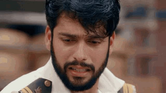 a man with a beard is crying with a tear coming out of his eye .
