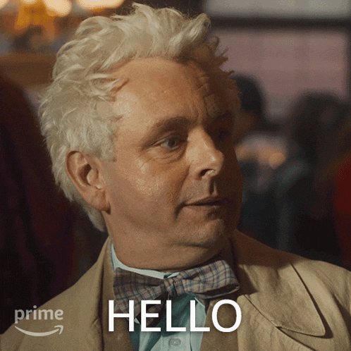 a man wearing a bow tie and a tan jacket says hello