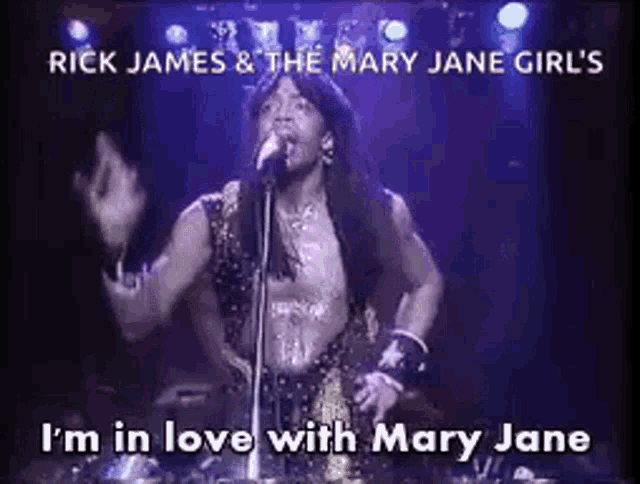 a man is singing into a microphone on a stage with the words `` i 'm in love with mary jane '' below him .