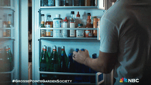 a man takes a bottle out of a refrigerator that has a nbc logo on it