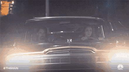 a man and a woman are driving a car on a street at night .