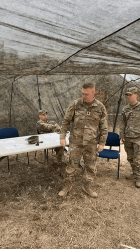 a man in a us army uniform is standing in front of a table and chairs