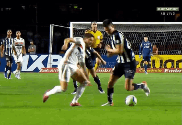 a group of soccer players are playing on a field with a premiere ad in the background