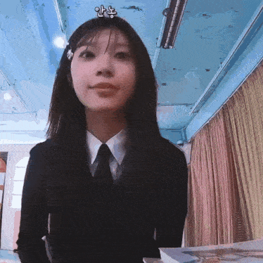 a girl wearing a black shirt and tie is standing in front of a blue curtain .