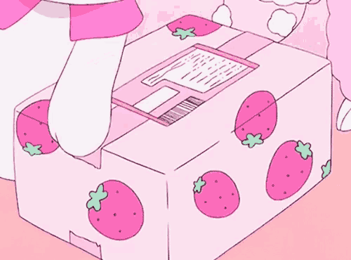 a pink box with strawberries on it and a cat standing next to it .