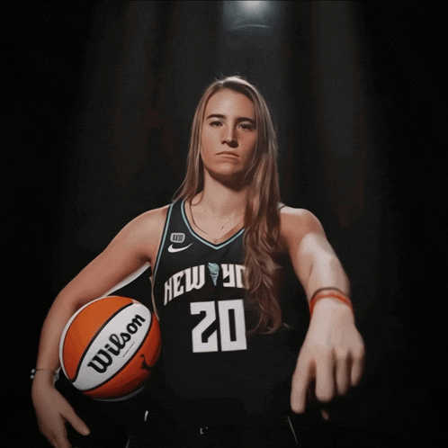 a woman holding a wilson basketball with the number 20 on it