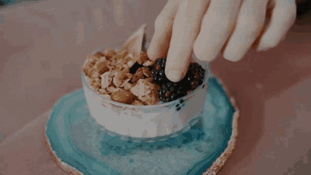 a person is putting berries into a bowl of yogurt