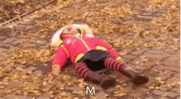 a child is laying on the ground in a pile of leaves .