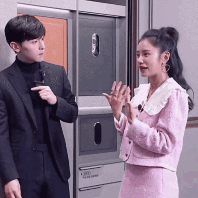 a man in a suit and a woman in a pink suit are standing next to each other