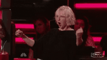 a woman in a black shirt is raising her fist in the air ..