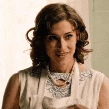 a woman wearing a white apron and a pearl necklace