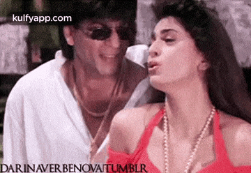 a man and a woman are standing next to each other and the woman is wearing a red tank top .
