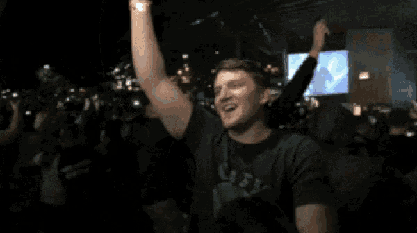 a man wearing a shirt that says ugly is dancing in a crowd