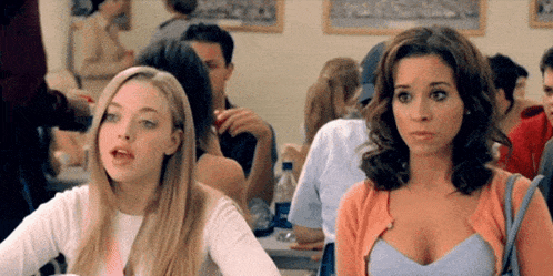 two women are sitting next to each other in a classroom with a crowd of people .