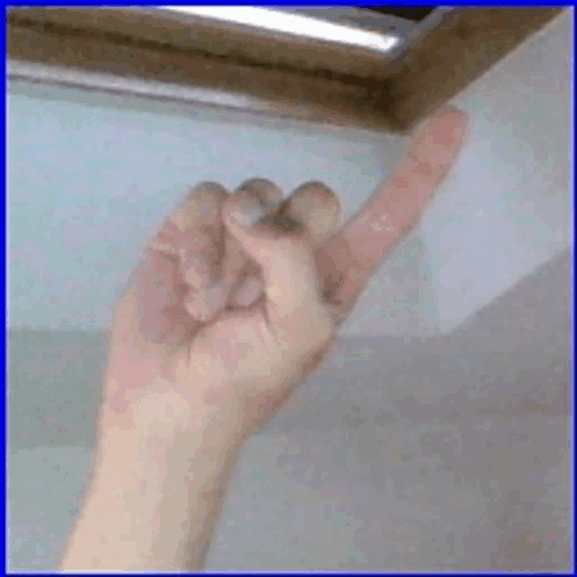 a close up of a person 's hand pointing to the ceiling