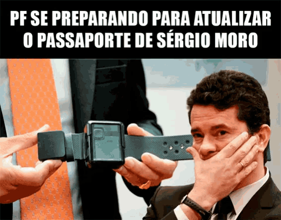 a man in a suit and tie is covering his mouth while another man holds a device
