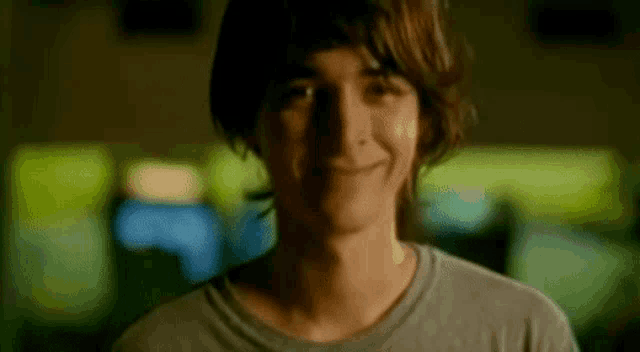 a young man is smiling and looking at the camera .