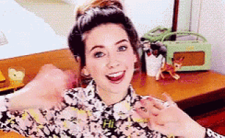 a woman in a floral shirt is smiling and giving a thumbs up sign .