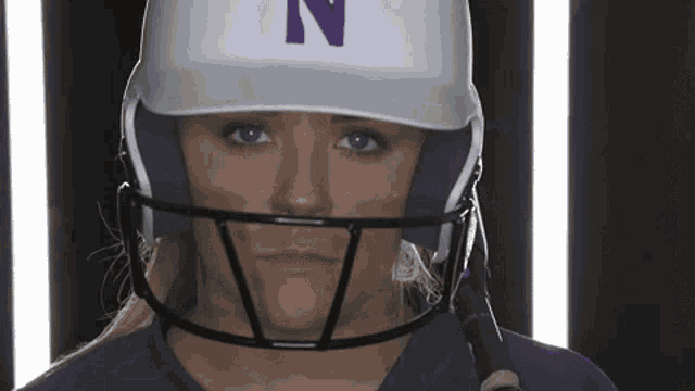 a woman wearing a baseball helmet with the letter n on the front