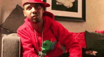 a man wearing a red hoodie and a red hat is sitting on a couch