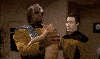 a man in a yellow uniform is holding a cat while another man looks on