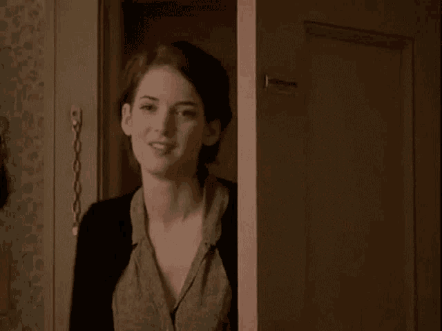 a woman is peeking out of a doorway and smiling at the camera .