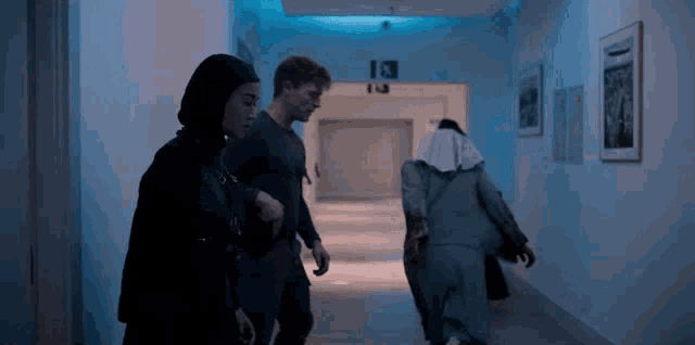 a group of people are walking down a hallway with a sign that says exit