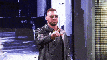 a man wearing sunglasses and a black leather jacket is pointing