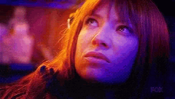 a close up of a woman 's face with purple lights behind her