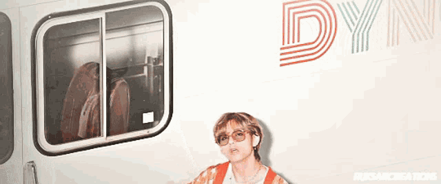 a man wearing sunglasses is standing in front of a white wall with the word dyn on it