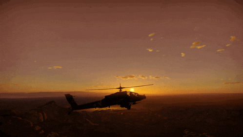 a silhouette of a helicopter flying over a desert at sunset