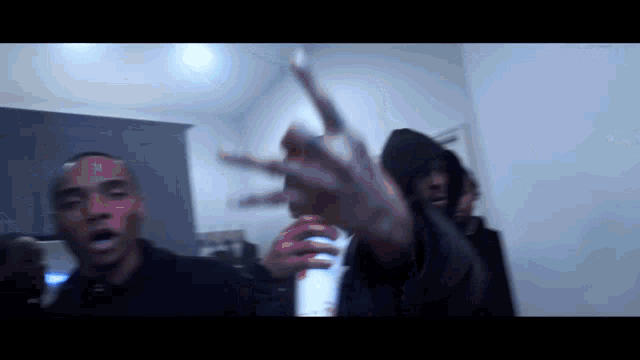 a man in a hooded jacket is holding a bottle and giving a middle finger .