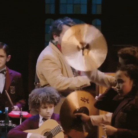 a man is holding a cymbal while playing a guitar