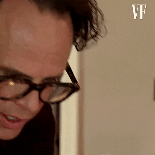 a close up of a man wearing glasses and looking down .