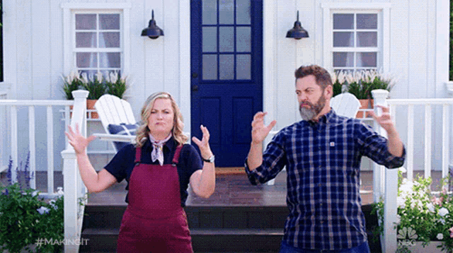 a man and a woman are standing in front of a house with a blue door ..