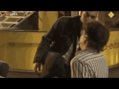 a man in a suit is kneeling down next to a woman in a striped shirt .
