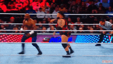 two wrestlers are fighting in a wrestling ring with a referee watching .