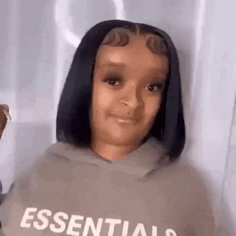a young girl with short black hair is wearing a hoodie and smiling .