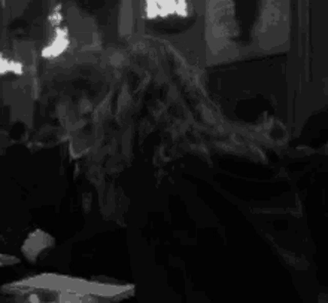 a woman is sitting at a table in a black and white photo .