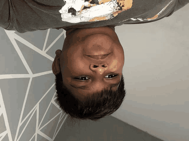 a young boy 's head is upside down and he is wearing a t-shirt with a bear on it