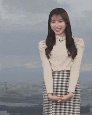 a woman wearing a plaid skirt and a white sweater smiles for the camera