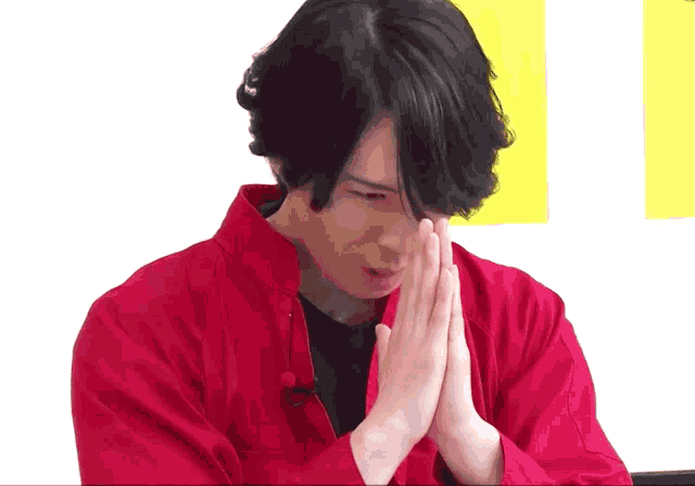 a man wearing a red jacket is praying with his hands together
