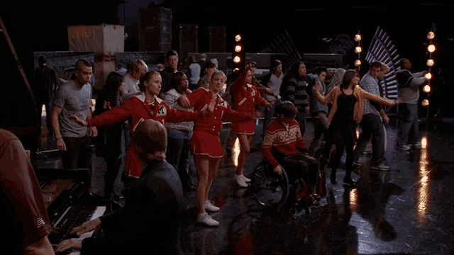 a man in a wheelchair is surrounded by people dancing