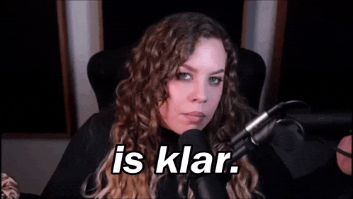 a woman is sitting in front of a microphone with the words `` is klar '' written on her face .