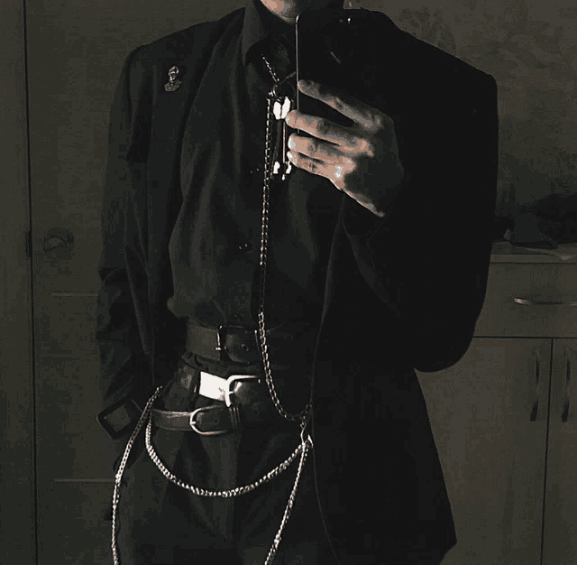 a man in a black suit is taking a selfie with his cell phone