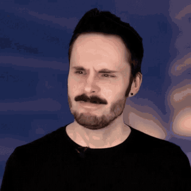 a man with a beard and mustache is wearing a black shirt and black earrings