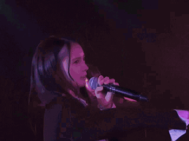 a woman singing into a microphone with a shadow on her face