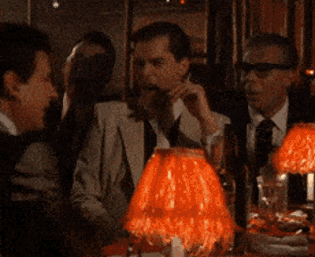 a group of men sitting around a table with red lamps on it