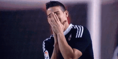 a man is covering his face with his hands while laughing .