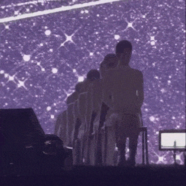 a group of people standing in front of a purple background .
